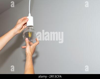 Light bulb and hands close-up, replacing bulb, energy saving, reduction electricity consumption. Stock Photo