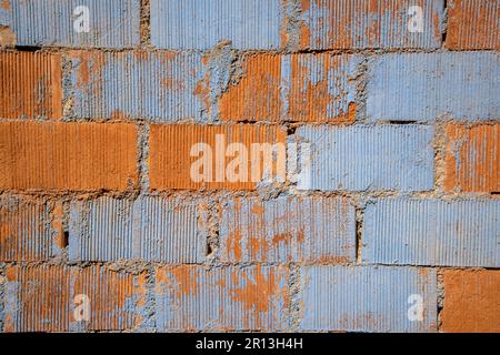 Peeling Paint on a Brick Wall in shades of grey and cream with spots of exposed Brick. The texture of red bricks. Stock Photo