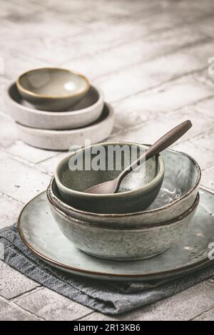 Gray stoneware plates and bowls on a rustic table, vertical with copy space Stock Photo
