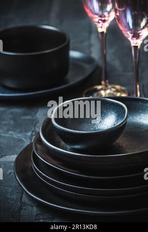 Black stoneware and pink shimmering champagne glasses on a rustic black table Stock Photo