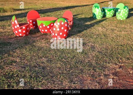 A set of tables, chairs or benches in the garden made of cement, shaped like strawberries. Stock Photo