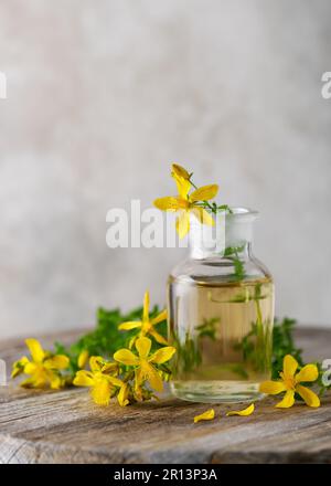 Medicine bottle with essential oil or infusion St. Johns wort flowers on wooden board outdoors. (Hypericum perforatum) Copy space. selective focus. Stock Photo