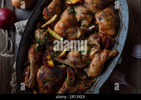 Sunday or holiday chicken meat dish with roasted apples and onions in roasting pan for autumn and winter season Stock Photo