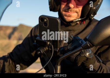 Biker setting the route on the gps map of his smartphone anchored to the handlebar Stock Photo
