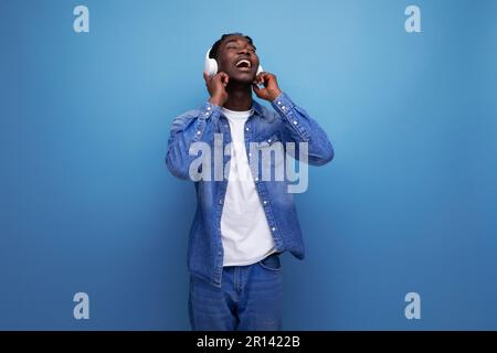 cool dude american man with dreadlocks in a denim jacket relaxes to music in headphones Stock Photo