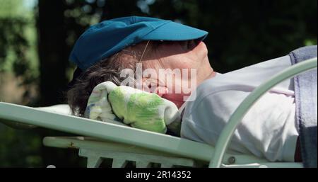 Older man asleep outdoors under a tree napping. Senior person sleeping during afternoon nap Stock Photo