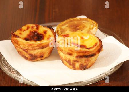 Pastel de Nata, Portuguese Custard Tarts on a plate with a Pastel shaped cinnamon shaker Stock Photo