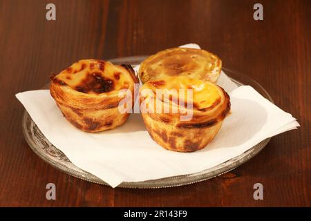 Pastel de Nata, Portuguese Custard Tarts on a plate with a Pastel shaped cinnamon shaker Stock Photo