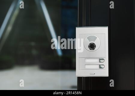 Modern intercom with camera hanging on door outdoors Stock Photo