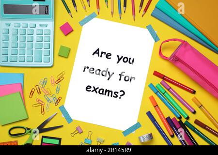 Paper with phrase Are You Ready For Exams and stationery on yellow background, flat lay Stock Photo