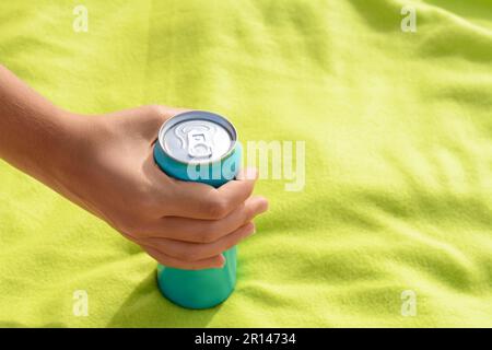 Woman holding aluminum can with beverage on yellow blanket, closeup. Space for text Stock Photo
