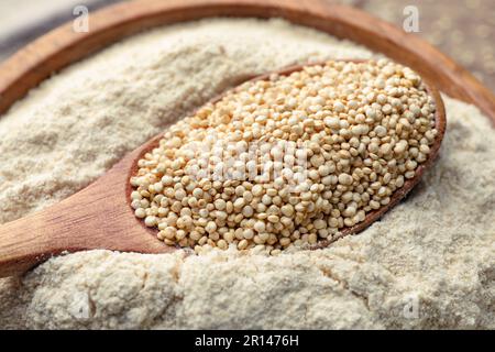 Wooden spoon with seeds on quinoa flour in bowl, closeup Stock Photo