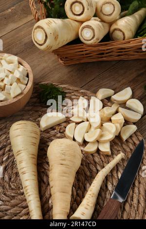 Whole and cut parsnips on wooden table, above view Stock Photo