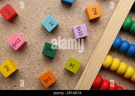 Wooden cubes with numbers and multiplications near abacus on fiberboard, flat lay Stock Photo