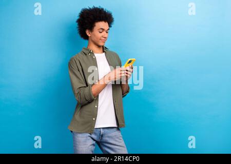 Photo of young concentrated blogger man writing his twitter speech hold smartphone wear stylish outfit isolated on blue color background Stock Photo