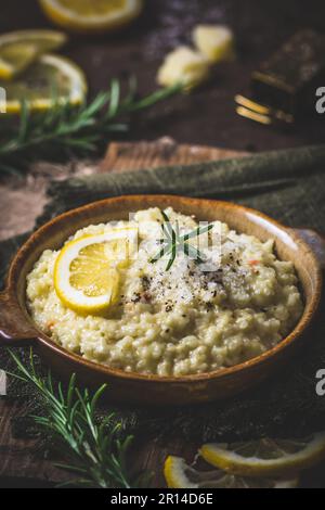 Lemon rice risotto with rosemary on dark wooden background, vertical Stock Photo