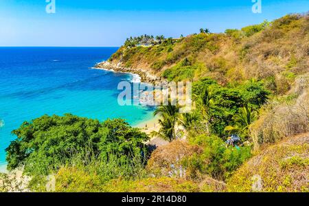 Beach sand turquoise blue water rocks cliffs boulders palm trees huge big surfer waves and panorama view on the beach Playa Carrizalillo in Puerto Esc Stock Photo