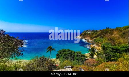 Beach sand turquoise blue water rocks cliffs boulders palm trees huge big surfer waves and panorama view on the beach Playa Carrizalillo in Puerto Esc Stock Photo