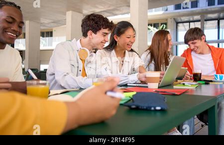 Group of cheerful high school students gather in college cafeteria to work and discuss topic test.  Stock Photo
