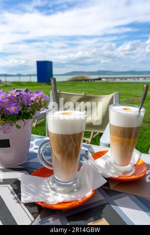drinking latte macchiato caffee together at lake Balaton in Hungary on the beach . Stock Photo