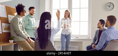 Young female coach or speaker giving presentation for employees in office. Woman trainer present business project on flip chart at meeting workshop Stock Photo