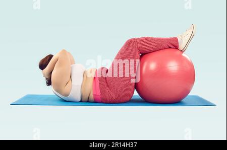 Overweight woman lying on sports mat and doing crunches exercise with Swiss ball Stock Photo