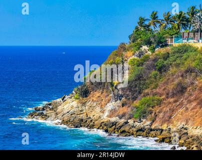 Beach sand turquoise blue water rocks cliffs boulders palm trees huge big surfer waves and panorama view on the beach Playa Carrizalillo in Puerto Esc Stock Photo