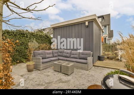 an outdoor living area with couches, tables and fire pit in the middle part of the yard on a sunny day Stock Photo