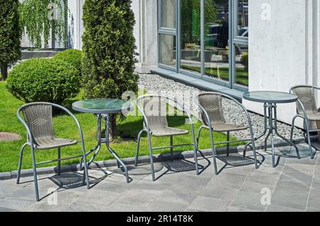 Wicker chairs and glass tables on summer terrace in sunny spring day Stock Photo