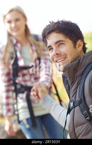 Hes the perfect gentleman. A handsome young hiker helping his girlfriend as they hike down a mountainside. Stock Photo
