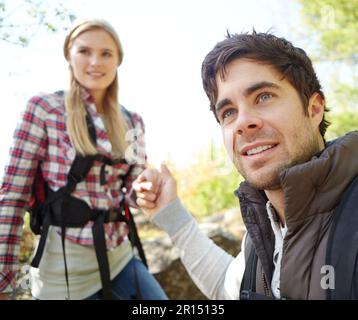 Helping her so she doesnt fall. A handsome young hiker helping his girlfriend as they hike down a mountainside. Stock Photo
