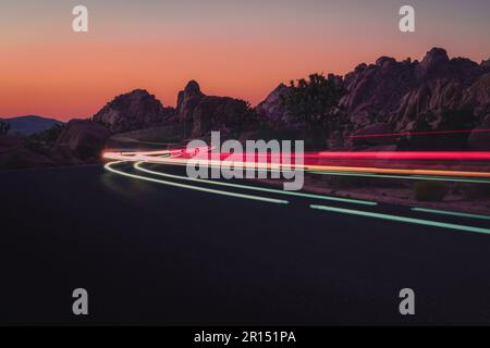 Light trails from cars driving through Joshua Tree National Park at sunset. Stock Photo