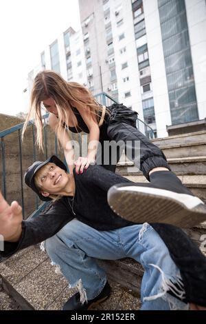 A teenage couple is having fun in the urban exterior and acting silly. Stock Photo