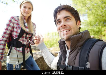 Careful now, watch your step...A handsome young hiker helping his girlfriend as they hike down a mountainside. Stock Photo