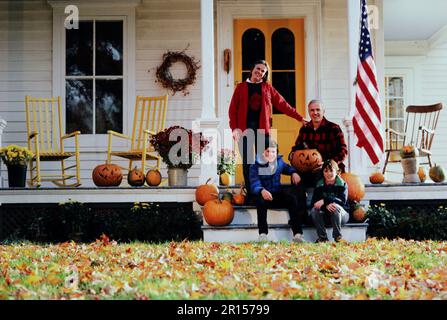 Family Portrait of a Caucasian family posing on the steps of there 19th century home in the fall Stock Photo
