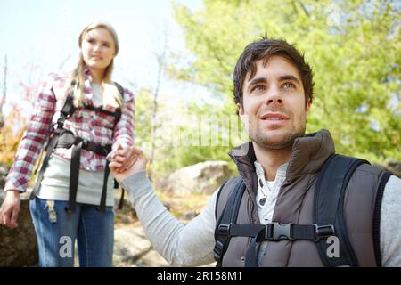 Leading the way to the bottom. A handsome young hiker helping his girlfriend as they hike down a mountainside. Stock Photo