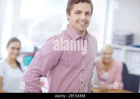You wont find a better leader. Portrait of a handsome young businessman with his colleagues in the background. Stock Photo