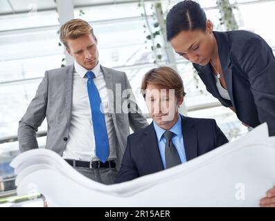 Satisfied with the plans... finally. A group of architects looking over some plans. Stock Photo