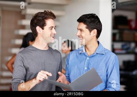 Weve got something amazing right here. Two friendly colleagues discussing a business portfolio in the office. Stock Photo