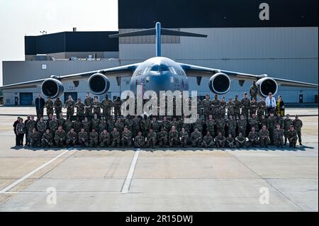 U.S. Air Force Airmen assigned to the 305th Air Mobility Wing pose for a flight line photo on 10 May, 2023 at Joint Base McGuire-Dix-Lakehurst, N.J. The 305th AMW extends America's global reach by generating, mobilizing and deploying KC-10 Extenders and C-17 Globemaster III’s to conduct strategic airlift and air refueling missions worldwide. In November 2021, the wing began transitioning to the new KC-46A Pegasus air refueling aircraft. Additionally, the Wing operates two of America's largest strategic aerial ports supporting the delivery of cargo and personnel to combatant commanders abroad. Stock Photo