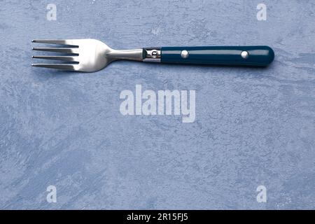 Stainless steel fork with plastic handle on grunge blue background Stock Photo