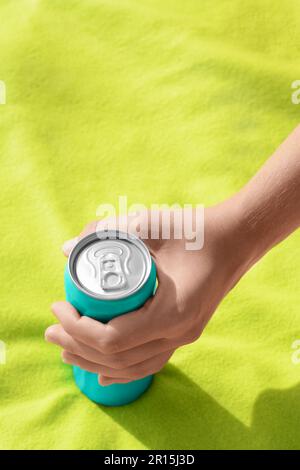 Woman holding aluminum can with beverage on yellow blanket, closeup Stock Photo