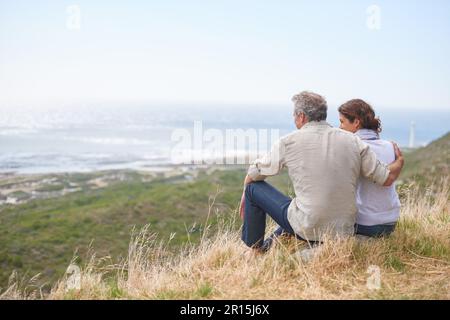 Taking in the scenery. Portrait of a mature couple sitting in the countryside. Stock Photo