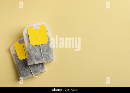 New tea bags with tabs on yellow background, flat lay. Space for text Stock Photo