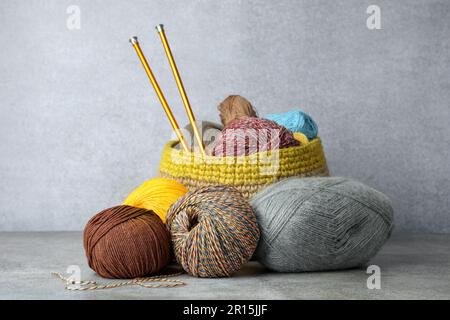 Soft woolen yarns and knitting needles on grey table Stock Photo