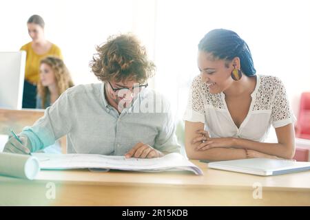 Working together for better results. two young designers working together in their office. Stock Photo