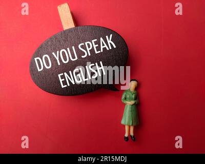 Wooden board and miniature people with the word DO YOU SPEAK ENGLISH on a red background Stock Photo
