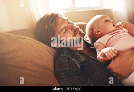 Whos putting who down to sleep. a young father and his baby daughter sleeping in the living room. Stock Photo