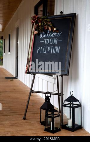 welcome to our wedding reception sign on an easel decorated with flowers and lanterns outside the wedding reception venue Stock Photo