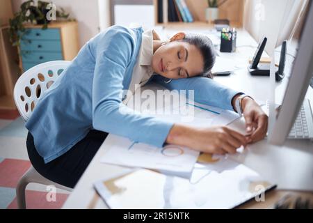 Burning the candle at both ends is never ideal. a young businesswoman sleeping at her desk in a modern office. Stock Photo